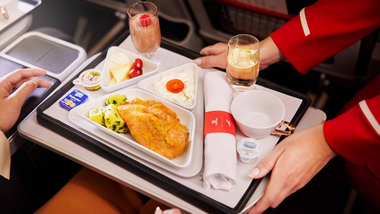 A food and drink tray on an airplane, showcasing a meal and a refreshing beverage in a compact airline setting.
