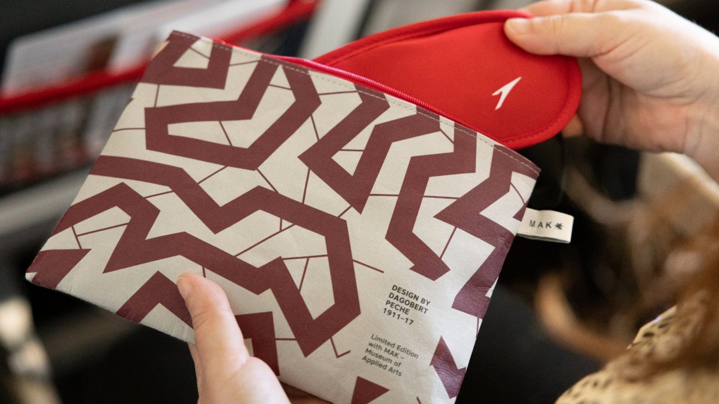 A woman displaying a red and white patterned bag, emphasizing luxury and style.