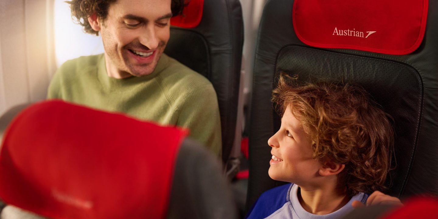 Smiling dad and son enjoying their flight with Austrian Airlines.