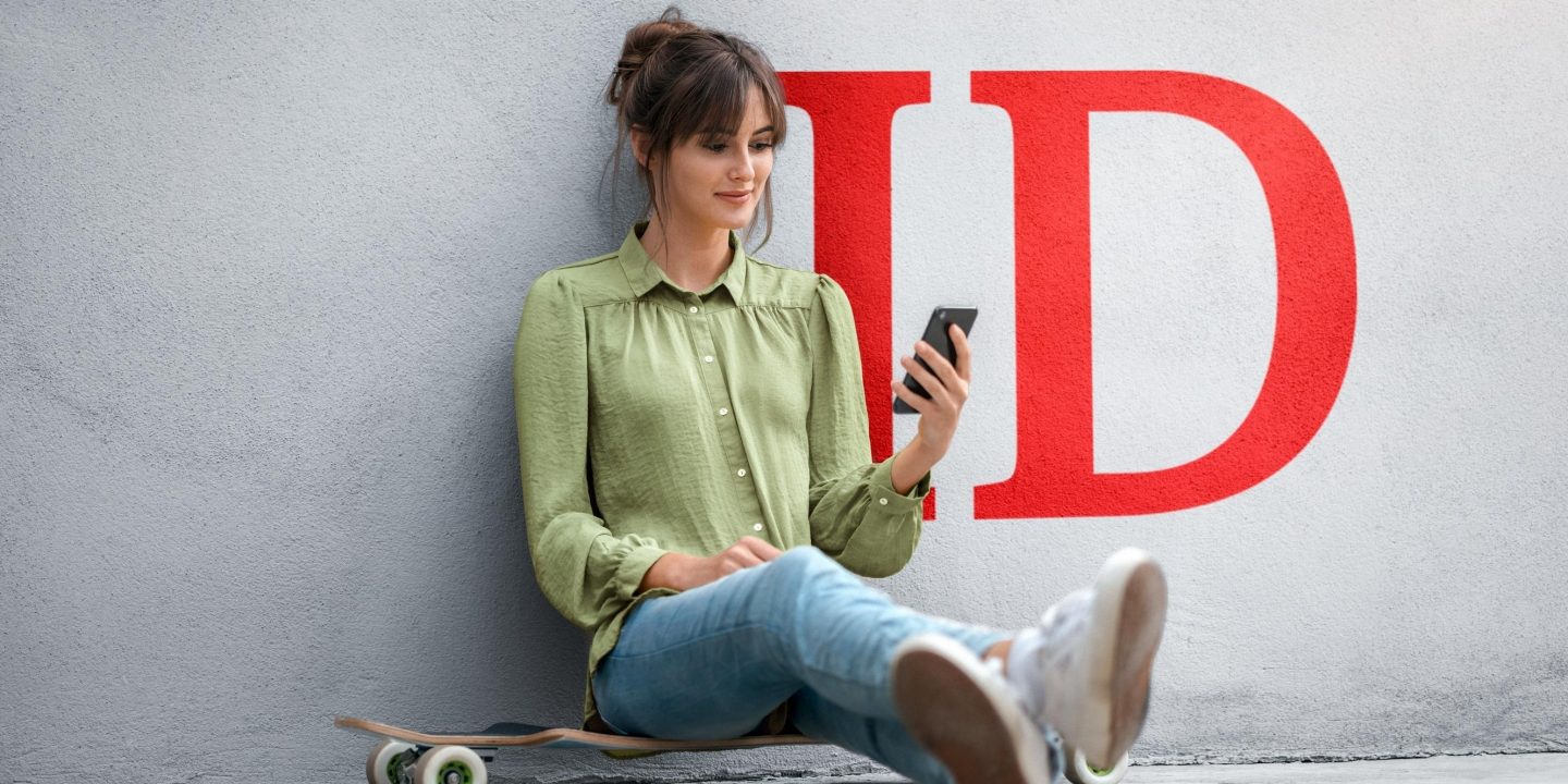 Una giovane donna seduta su uno skateboard consulta le condizioni sul suo smartphone