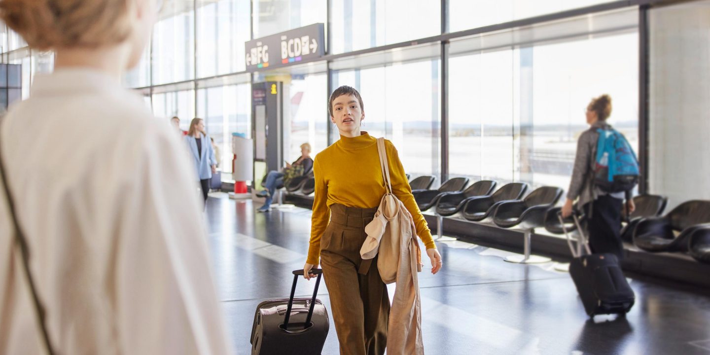 Frau mit Rollkoffer am Flughafen.