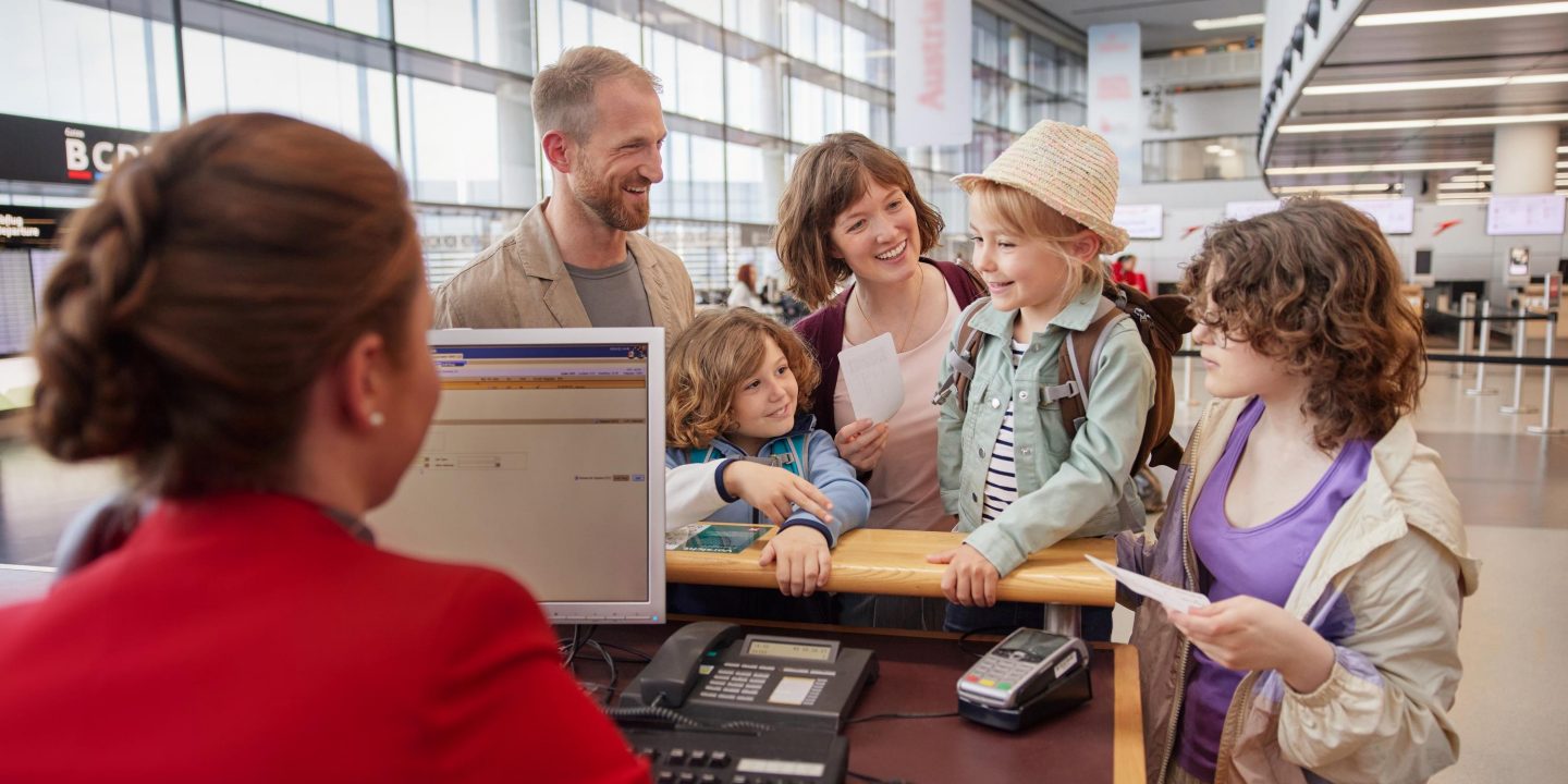 Happy family at an airport check-in counter assisted by an airline agent.