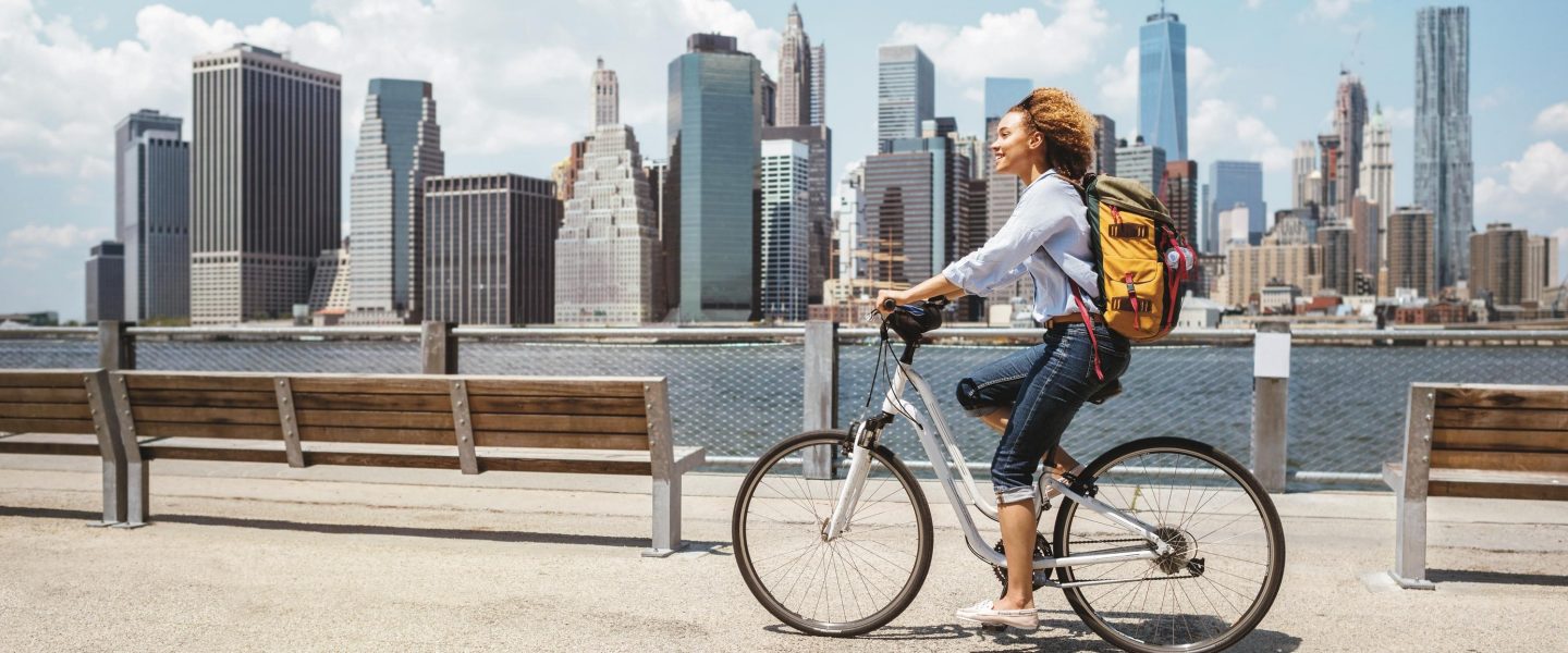 African American woman riding a bike in NYC on a beautiful summer day - transporastion concepts