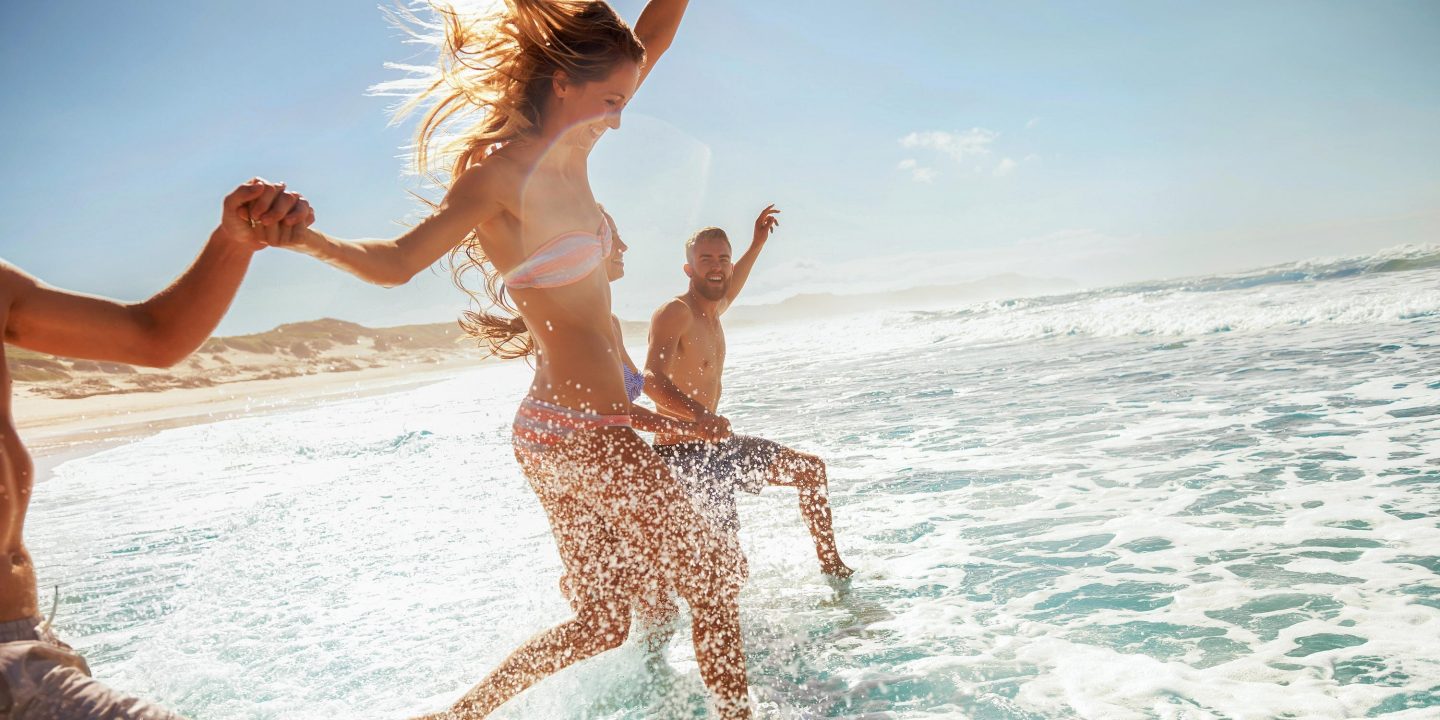 Two young couples running through the water at the beach