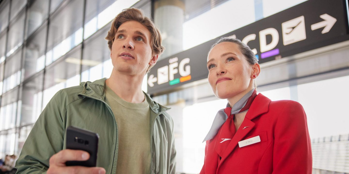 Eine Mitarbeiterin der Austrian und ein Mann am Flughafen.