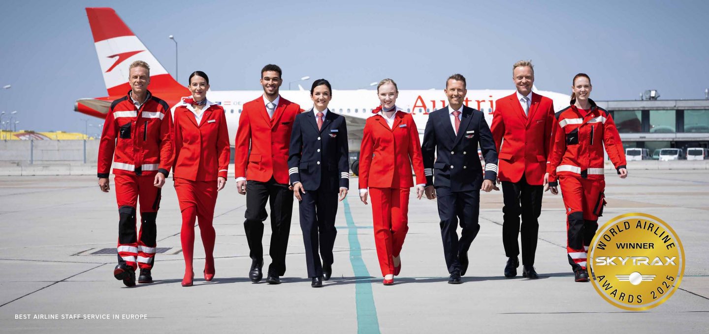 Airline crew and ground staff on the tarmac with an Austrian Airlines plane.