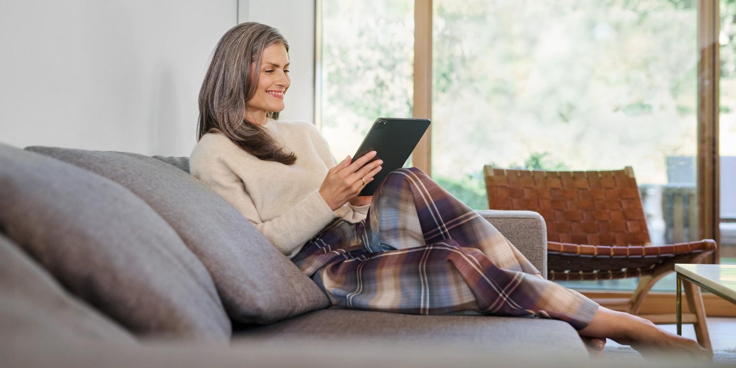Una donna sul divano che guarda il suo iPad e ride