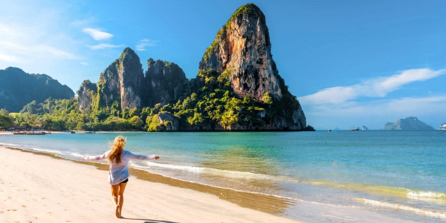 Frau am sonnigen Strand in Bangkok mit türkisblauem Meer und hellem Sand.