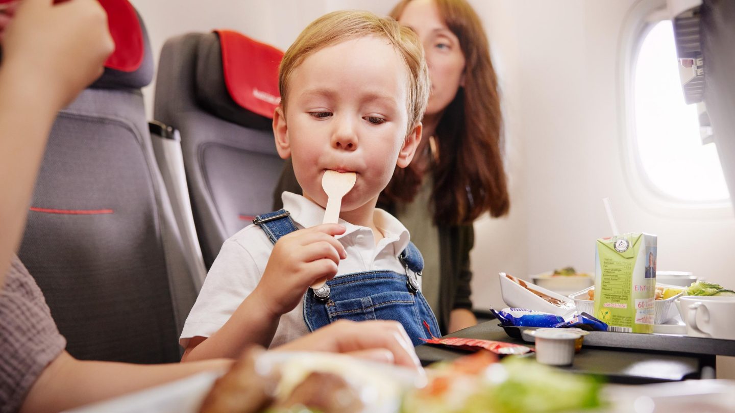 Kind sitzt im Flugzeug mit einem Kindermenü
