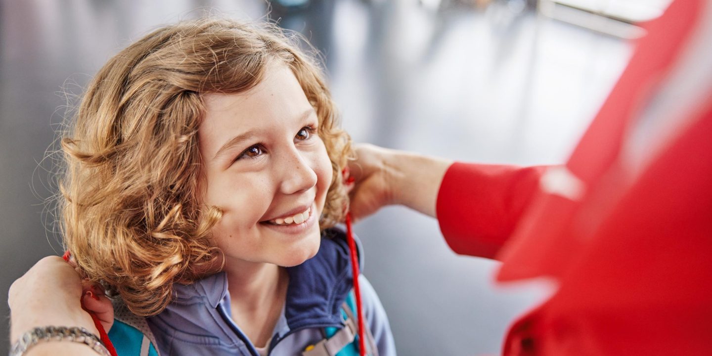 Smiling child having a red lanyard placed around neck