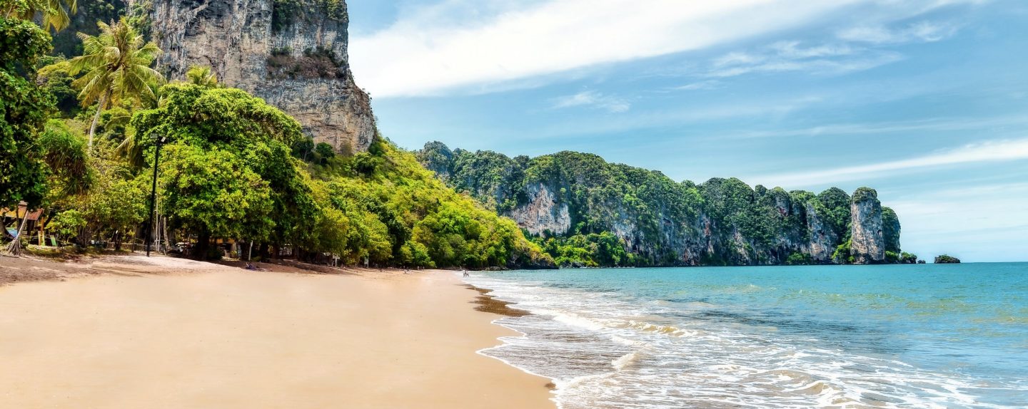 Frau am sonnigen Strand in Bangkok mit türkisblauem Meer und hellem Sand.