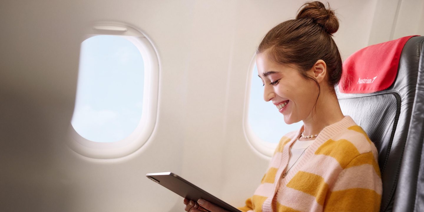 Smiling woman using tablet at airplane window seat