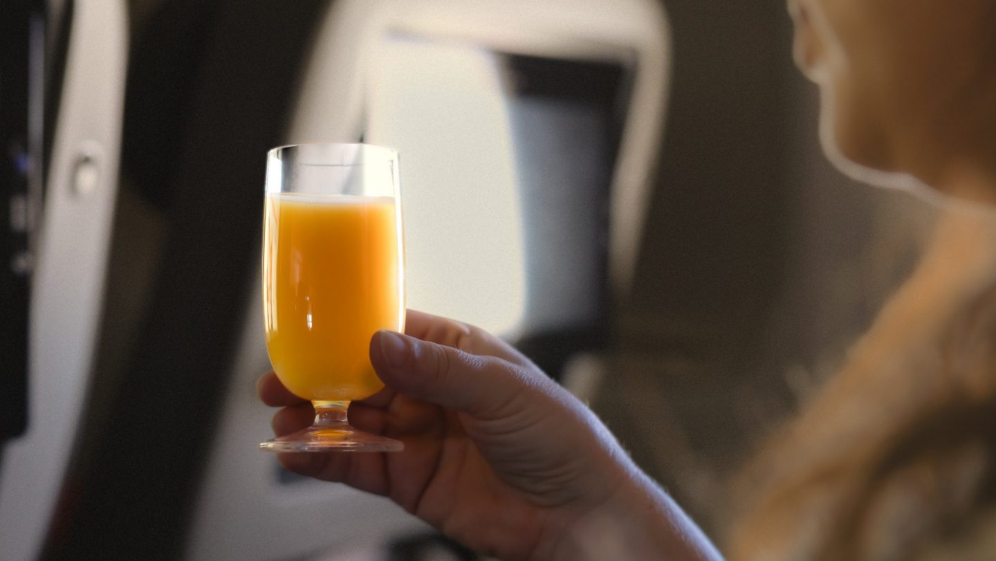 Person hält ein Glas Orangensaft