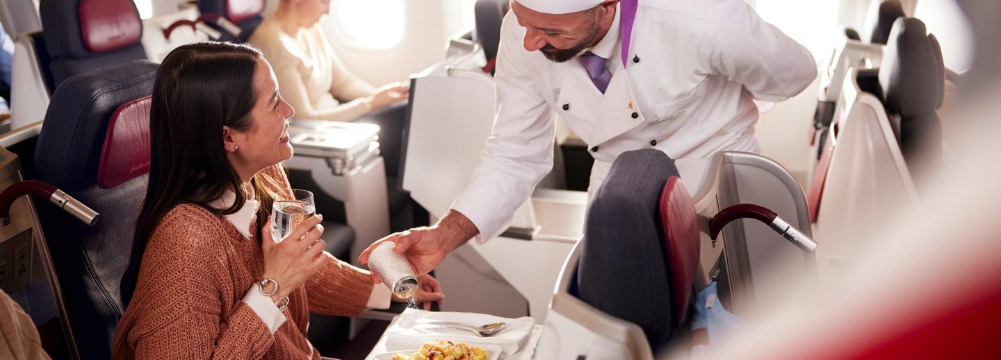 Chef on board the aircraft sprinkling salt onto a dish.