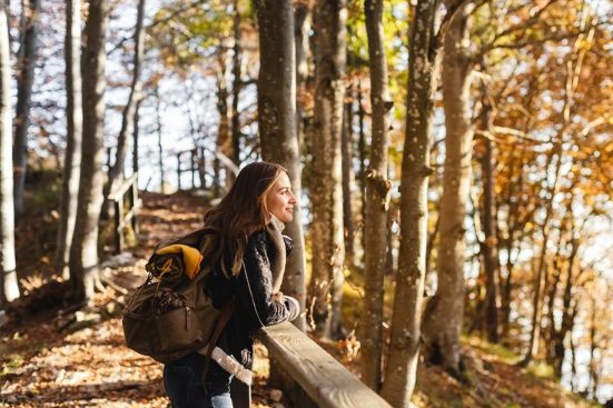 Frau in einem sonnendurchfluteten Wald, umgeben von üppigem Grün.