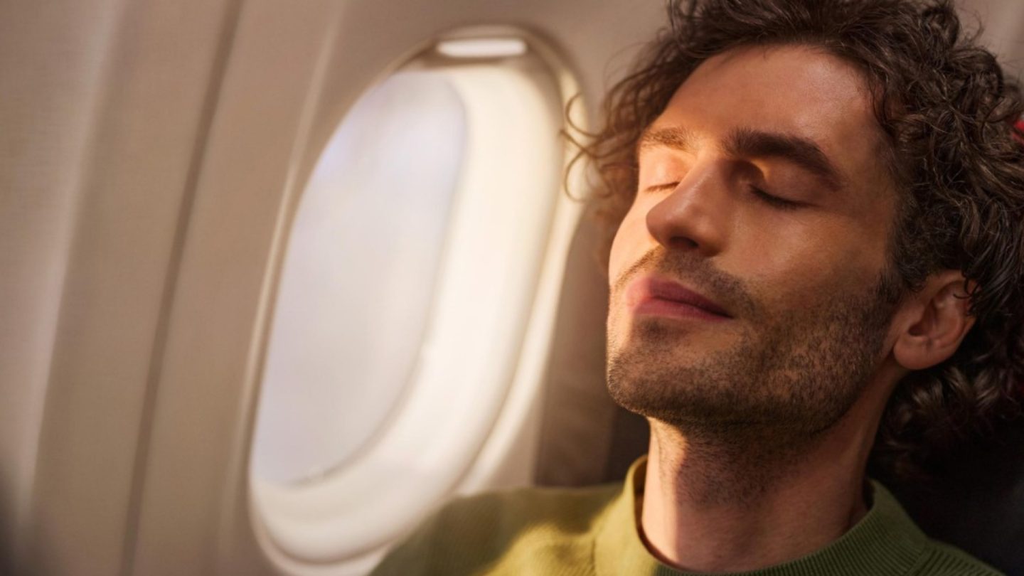 Ein Passagier schläft entspannt auf einem Flug, das Gesicht von der Sonne beschienen.