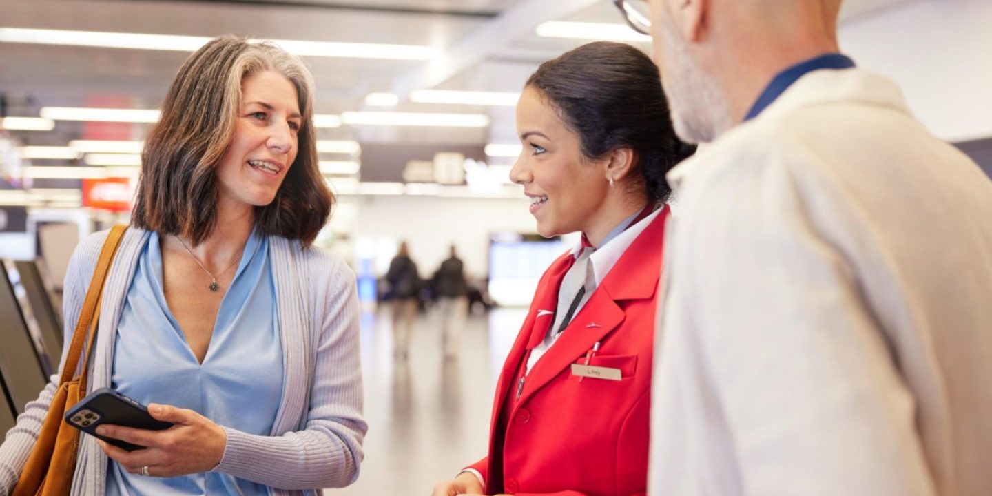 Ein Flugagent unterstützt zwei Passagiere auf einem Flughafen.