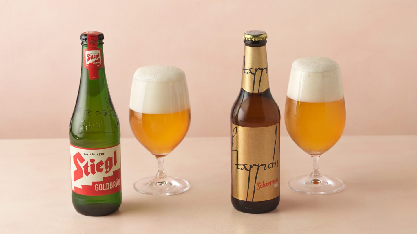 Two bottles of beer next to two glasses of beer with foam.