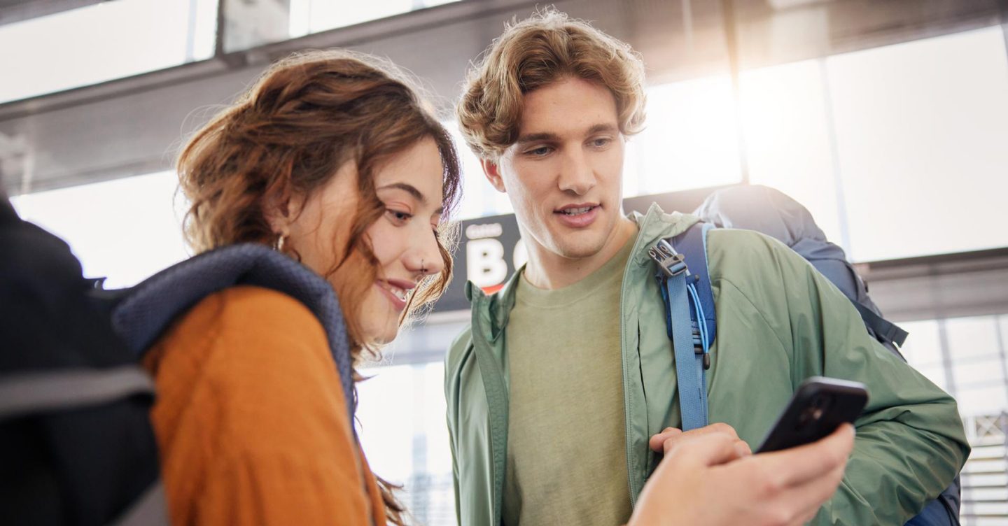 Two students at the gate checking their boarding pass on the phone.