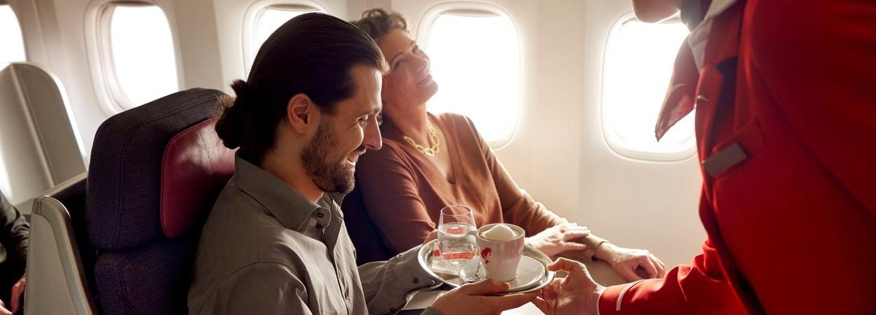 Paar sitzt in Flugzeug und bekommt ein Getränk serviert