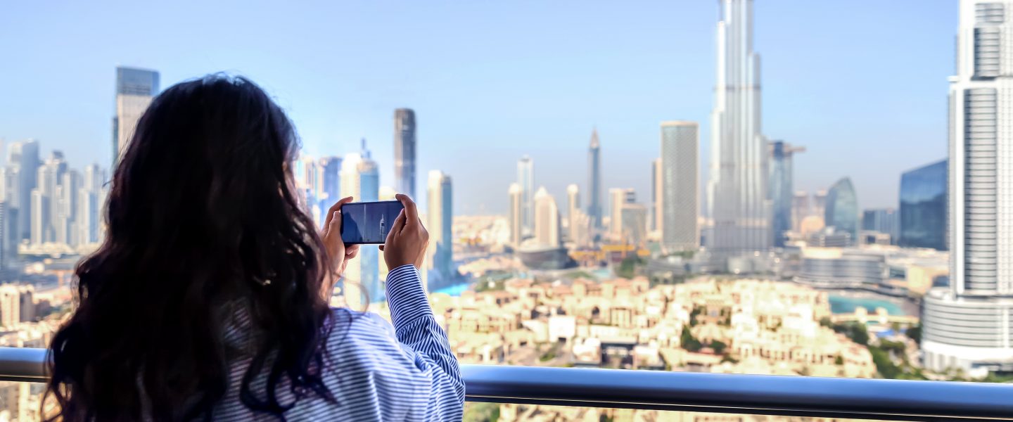 The woman taking photo on balcony of skyscraper in Dubai.