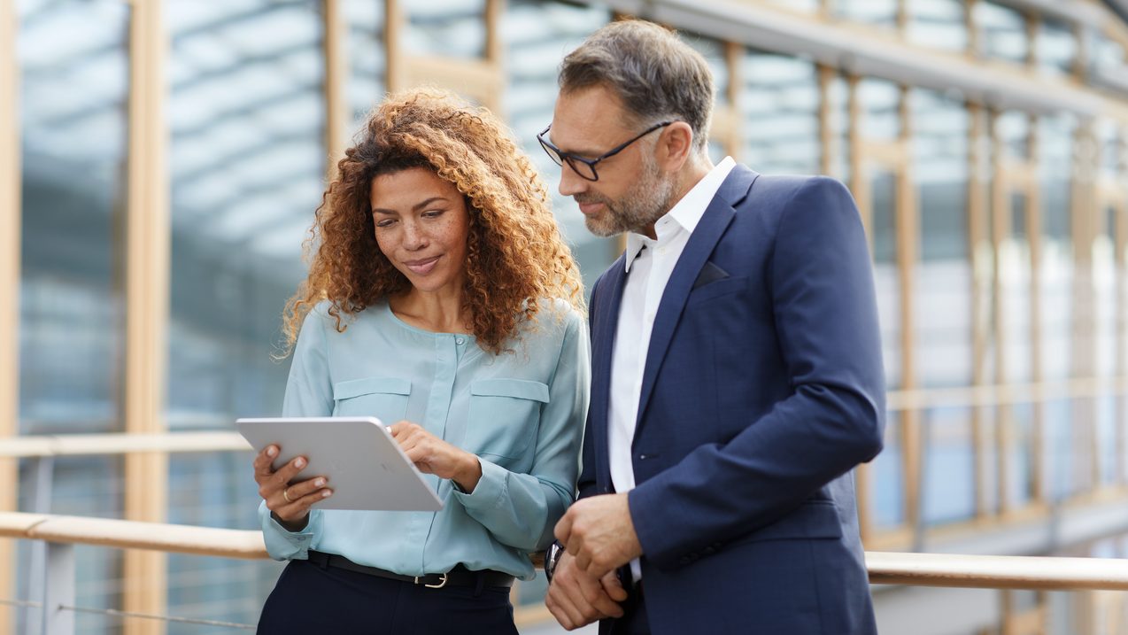 Woman uses tablet to present something to a colleague outside