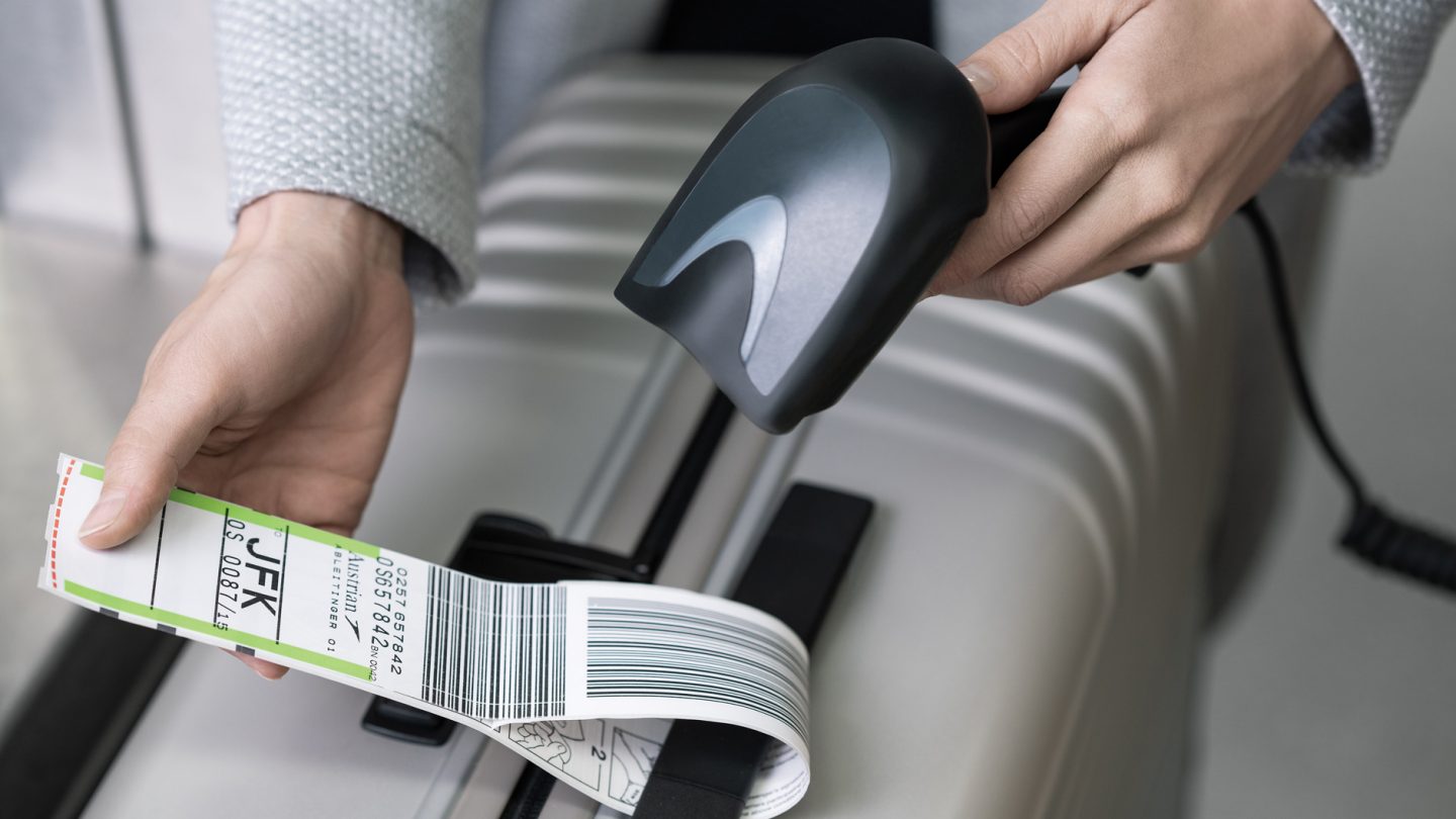 A person scans the luggage tag on their suitcase