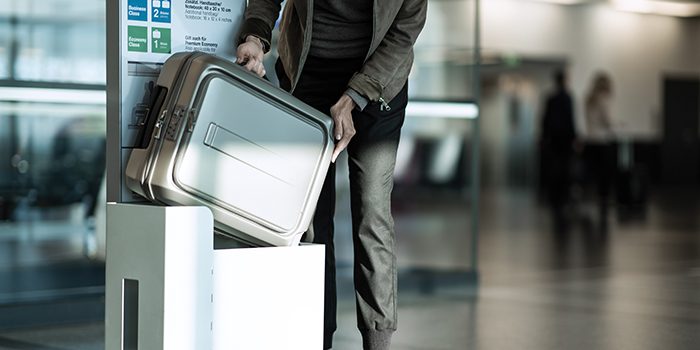 A man checks the size of his hand luggage at the airport