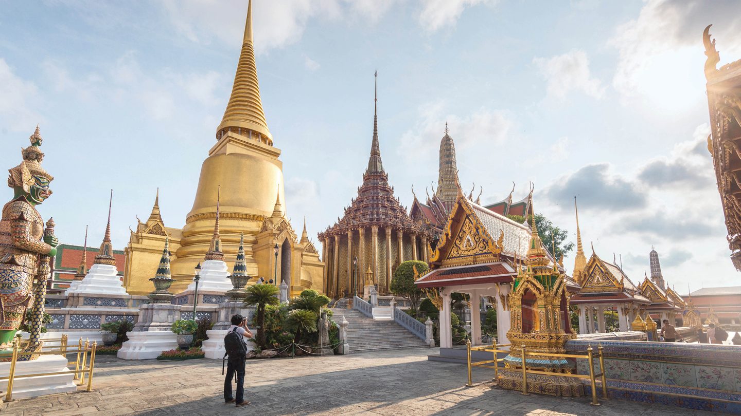 A tourist photographing a temple in Bangkok