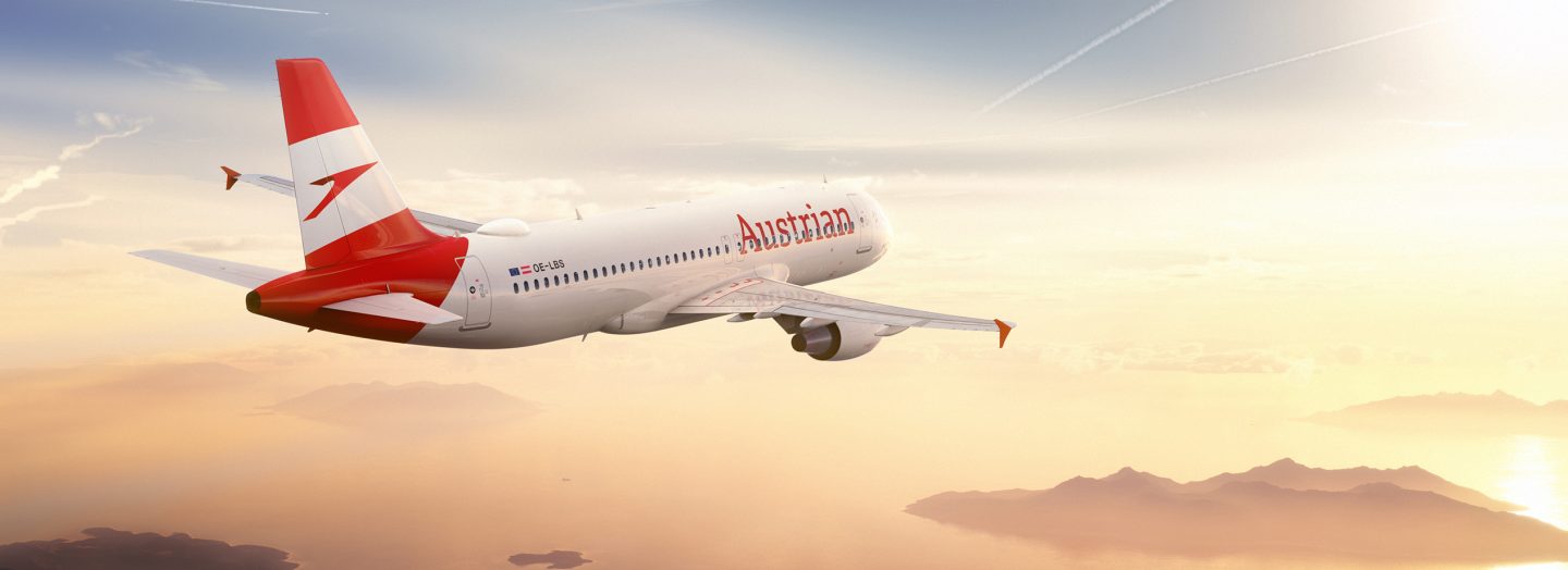 Airplane with Austrian Airlines foiling flies into the sunset