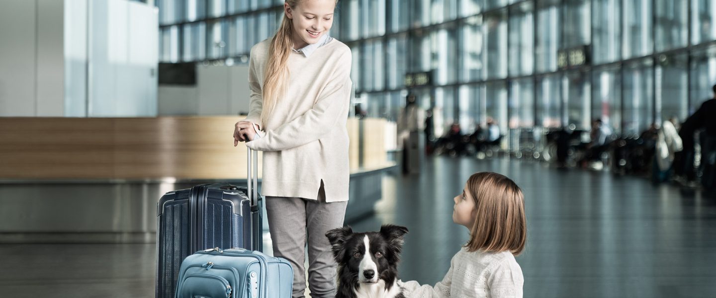 Two children with a dog and luggage at the terminal