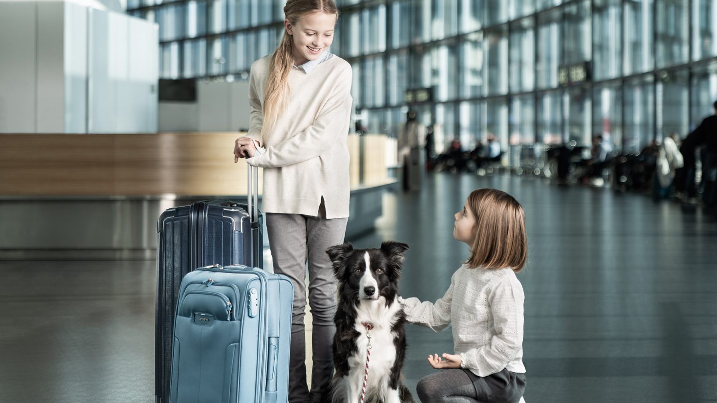 Two children with a dog and luggage at the terminal