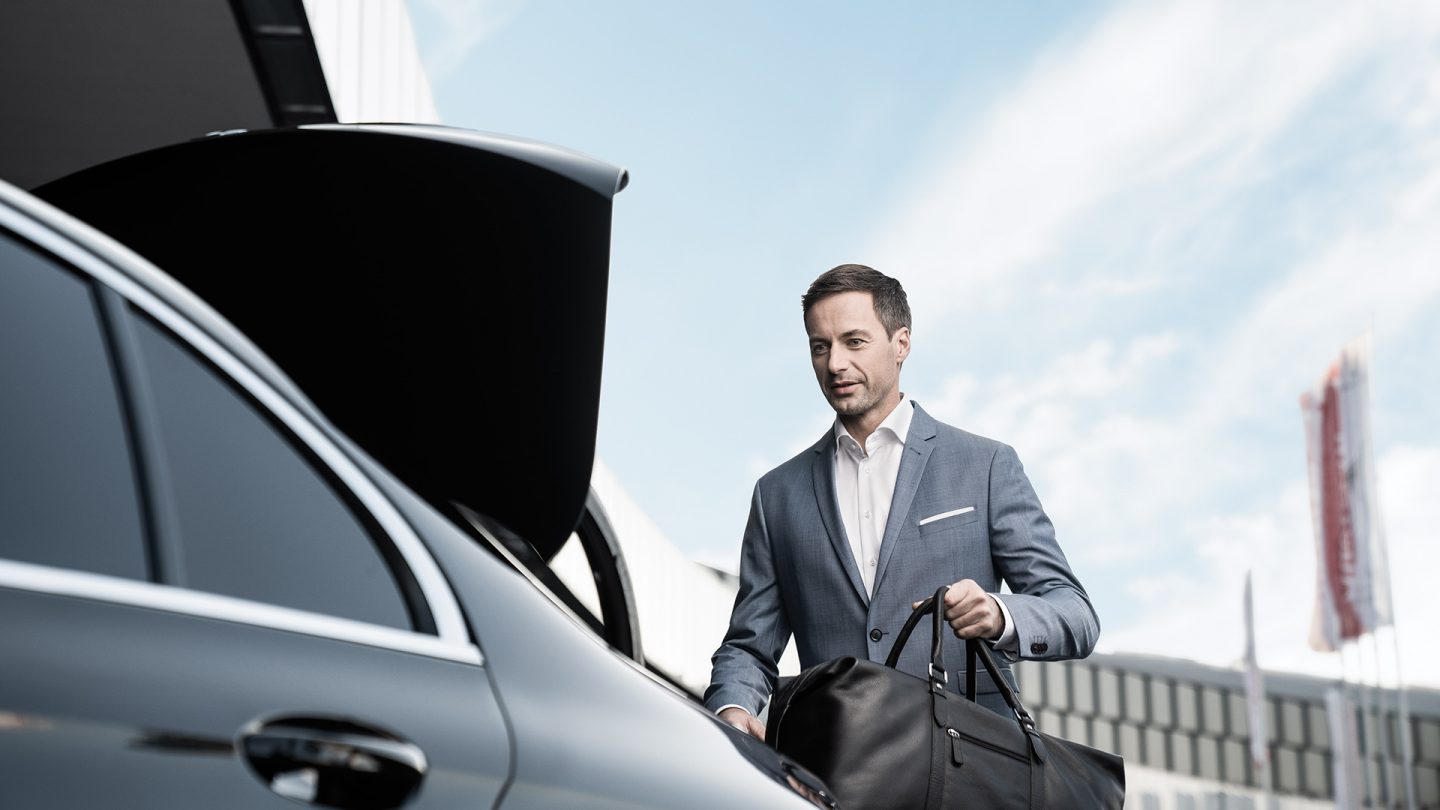 Business man loads his travel bag into the luggage space