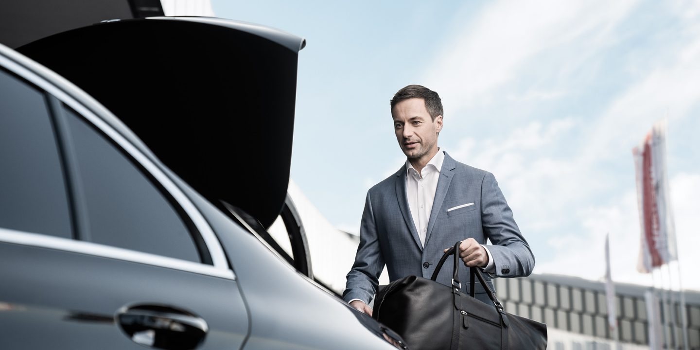 Business man loads his travel bag into the luggage space