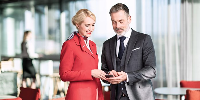 A passenger and a flight attendant look at a smartphone