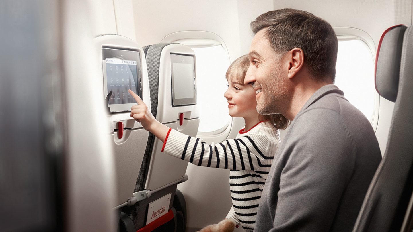 Father and daughter use the range of games on board an Austrian airplane
