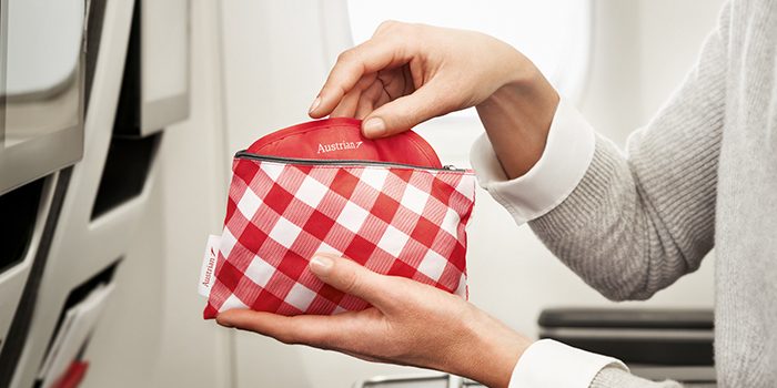 A woman holds an amenity kit from Premium Economy Class