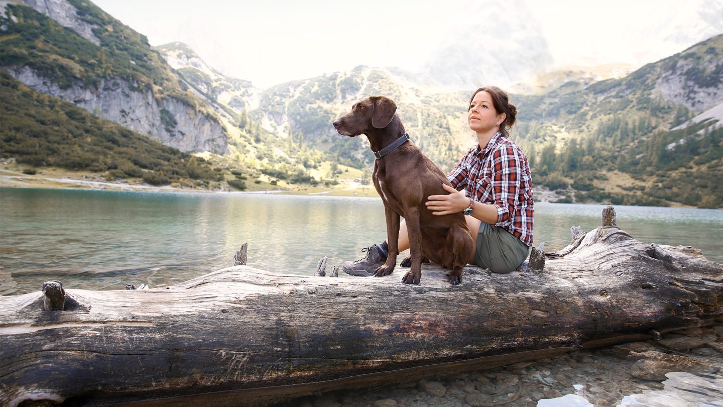 Woman with dog at a mountain lake