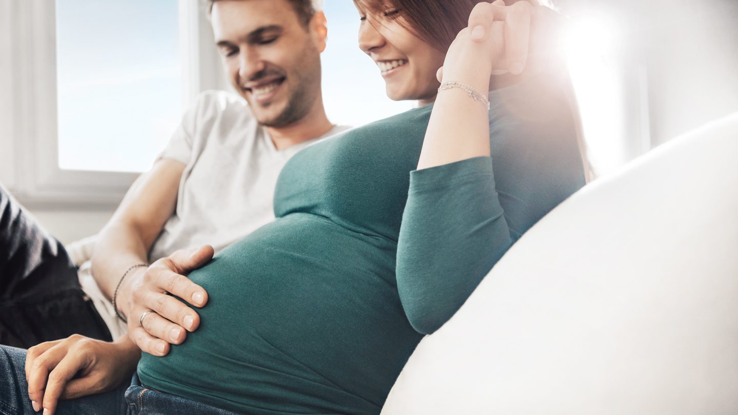A man holds his hand on the belly of his pregnant wife
